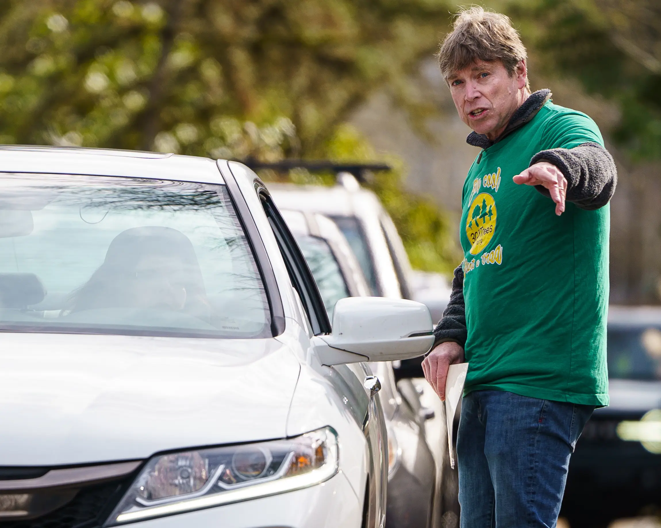 A 300Trees volunteer in a green shirt directing a car at a giveaway